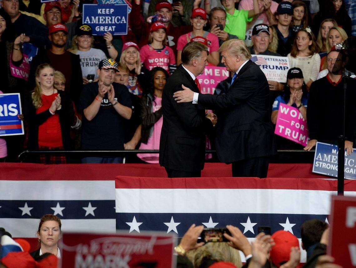 President Donald Trump shakes hands with GOP candidate Mark Harris, left, as he speaks at Bojangles Coliseum Friday night..