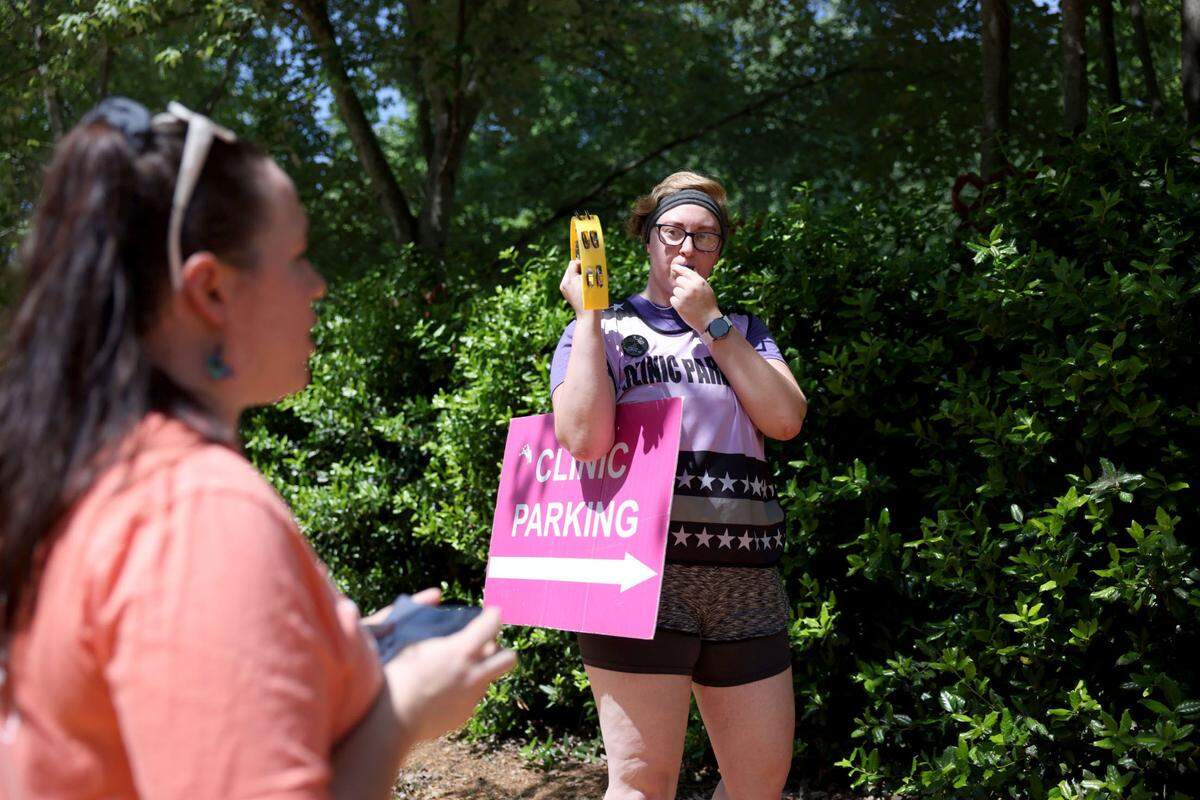 Nicole Fleming, right, blows a whistle to drown out a pro-life group “Love Life” during a protest at A Preferred Women’s Health Center of Charlotte Tuesday May 3, 2022.