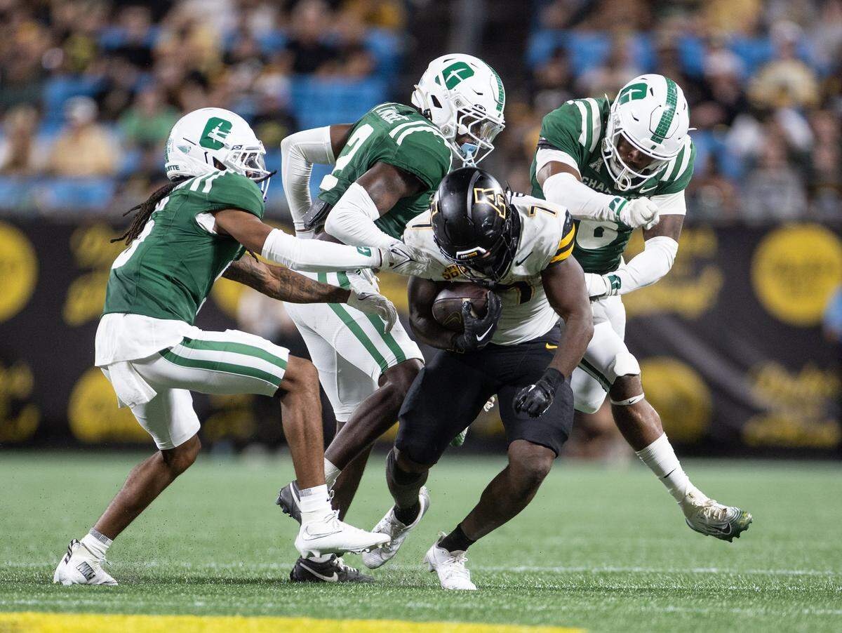 Appalachian State Mountaineers running back Rashod Dubinion, center, is tackled by a host of Charlotte 49ers defenders during the Duke's Mayo Classic at the Bank of America Stadium in Charlotte, N.C., on Friday, August 29, 2025.