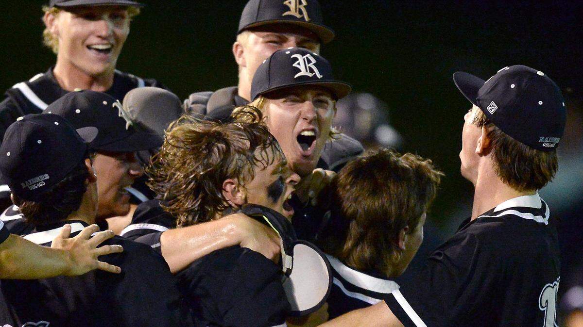 Reagan High pitcher Josh Hartle, center, is mobbed by his teammates following the final out against Providence High in NC 4A state semifinals action on Tuesday, June 22, 2021. Reagan High defeated Providence 7-3.