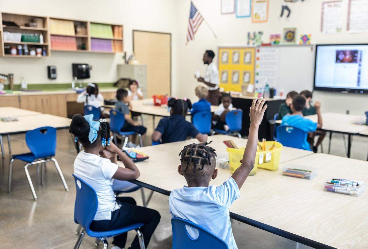 A student raises his hand in art class during the first day of school at Shamrock Gardens Elementary School in Charlotte, N.C., on Monday, August 29, 2022.