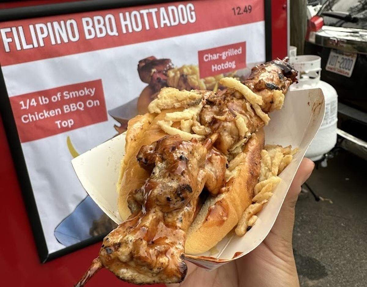 This hot dog comes from the food truck Hottadogs is made with a pork BBQ skewer on top, Filipino banana ketchup and crispy onions.