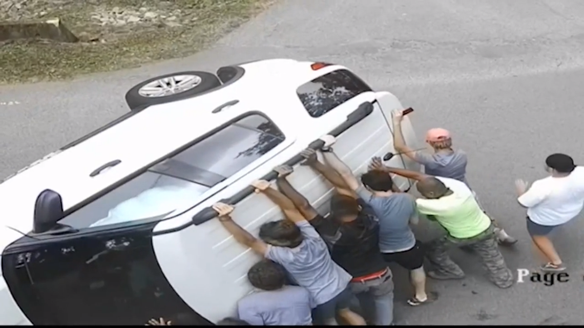 Video screenshot of eight golfers and construction workers rushing to help man after his SUV flipped in Belle Meade, Tennessee.