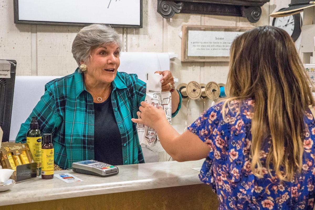 Lynn Broadway, employee at The Beehive Gifts in uptown’s Overstreet Mall, helps customers on Thursday, July 29, 2021. “When the workforce is gone from uptown Charlotte, so is our customer base,” she said.