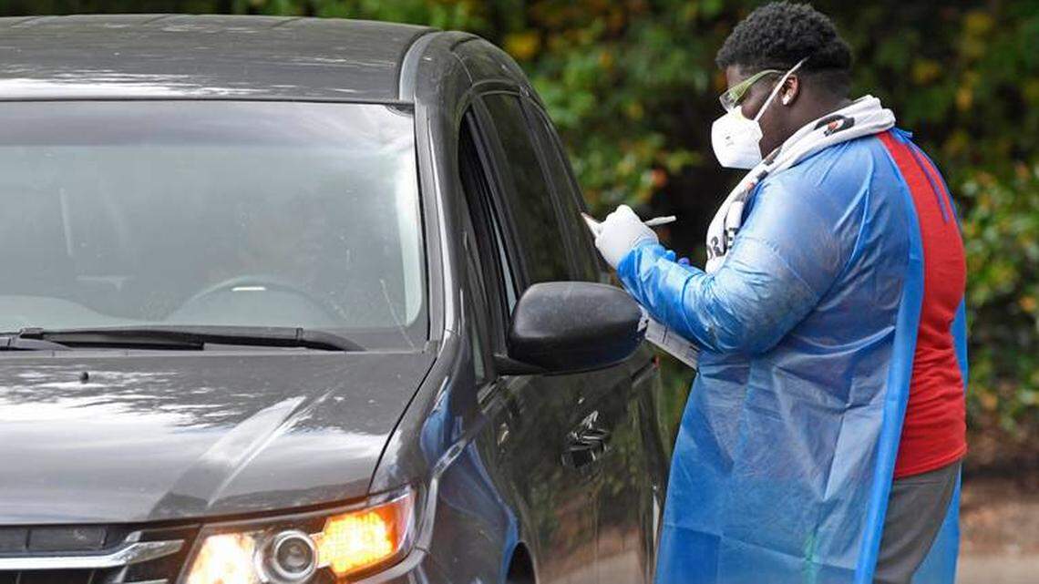 A healthcare professional works with a motorist at a Mecklenburg County Health Department drive-up COVID-19 testing site in late October. Over the last 30 days, cases among county residents have increased by more than 115%, according to an Observer analysis of public health data.