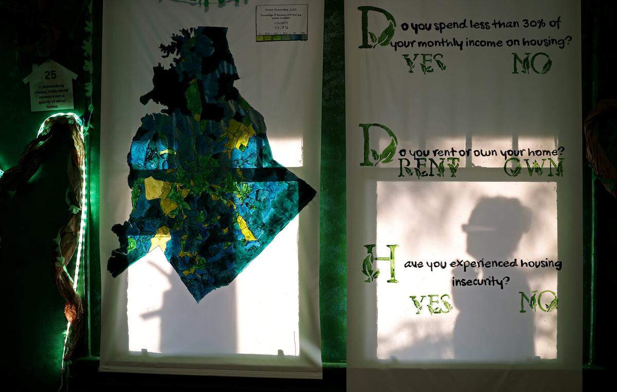 Hazel Doherty, right, is silhouetted on the blind of a window with questions audience members will be asked to consider during an immersive play on gentrification. QC Family Tree’s Big Blue House in Charlotte, NC will be hosting the upcoming play.