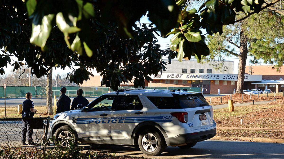 Charlotte-Mecklenburg police officers stand watch outside of West Charlotte High School along Senior Drive on Monday, December 13, 2021. Officials say the a fight over a book bag led to gunfire on the campus.
