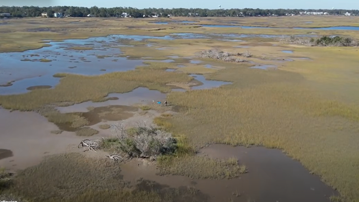 A skydiver making a first-time solo jump was left trapped in a marsh on Oak Island, North Carolina, after overshooting the landing zone, officials say.