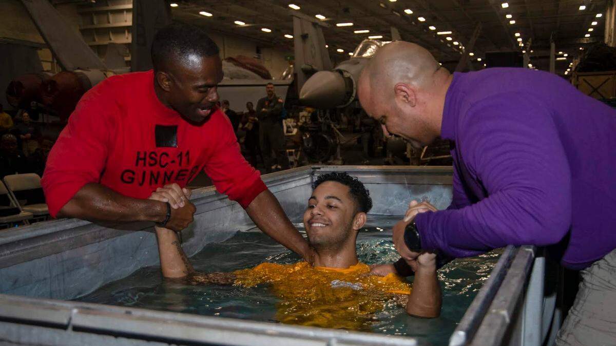 Jorden Burrows, a Navy airman apprentice from Denver, N.C., gets baptized in the hangar bay of the Nimitz-class aircraft carrier USS Harry S. Truman in the Atlantic Ocean on April 26, 2020. The Harry S. Truman Carrier Strike Group remains at sea as a certified carrier strike group force ready to go wherever needed, but also to protect the crew from COVID-19, the disease caused by the novel coronavirus, according to the Navy.