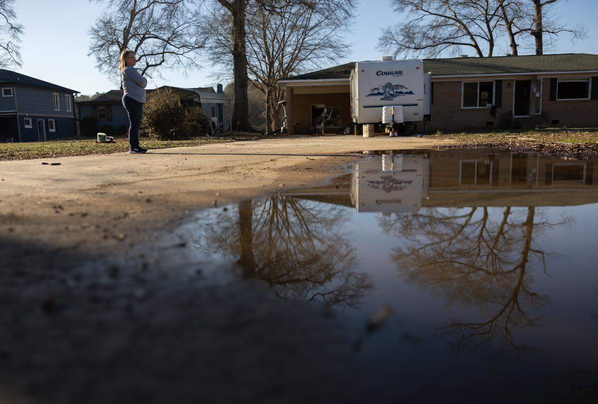 Melanie Kinley stands in front of Macie Kinley Lambert’s Lake Drive home in Charlotte this month. All six Kinley families that were living in the neighborhood when it flooded have decided to move.