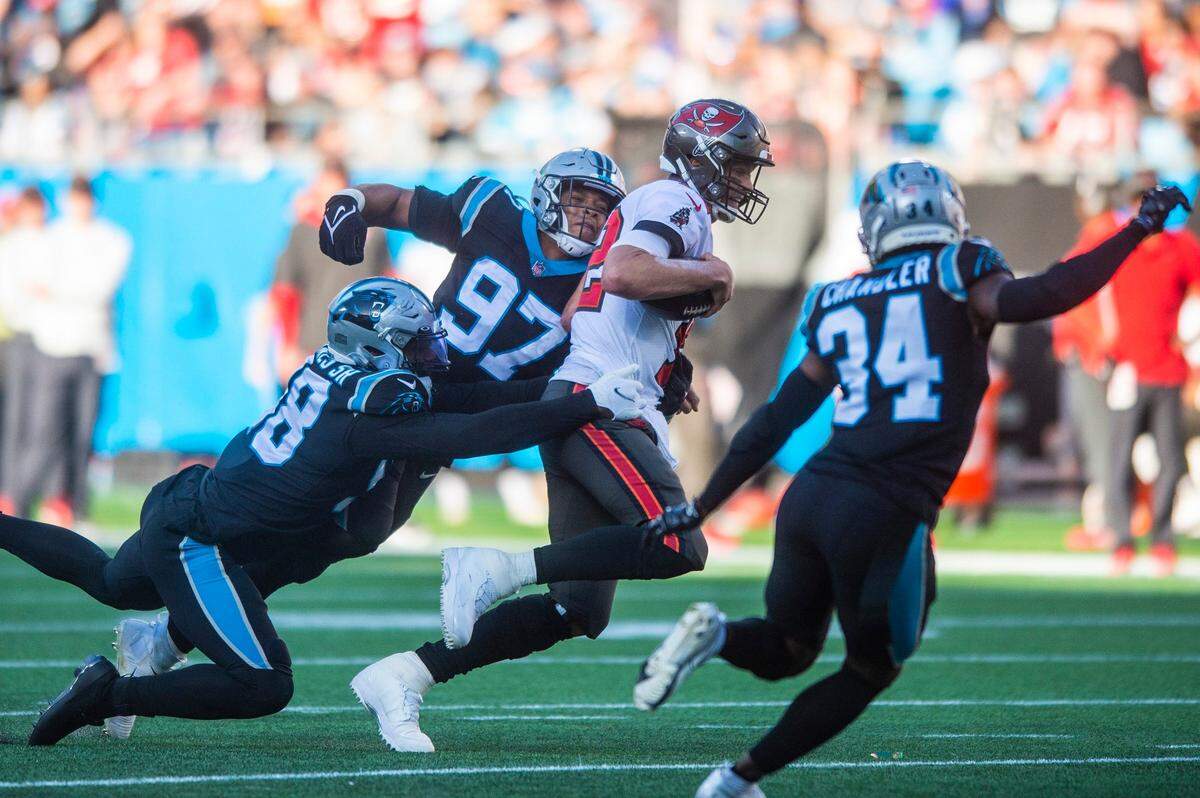 Panthers defense swarms Buccaneers quarterback Tom Brady, center, as he scrambles on a quarterback keeper during the game against the Buccaneers at Bank of America Stadium on Sunday, December 26, 2021 in Charlotte, NC.