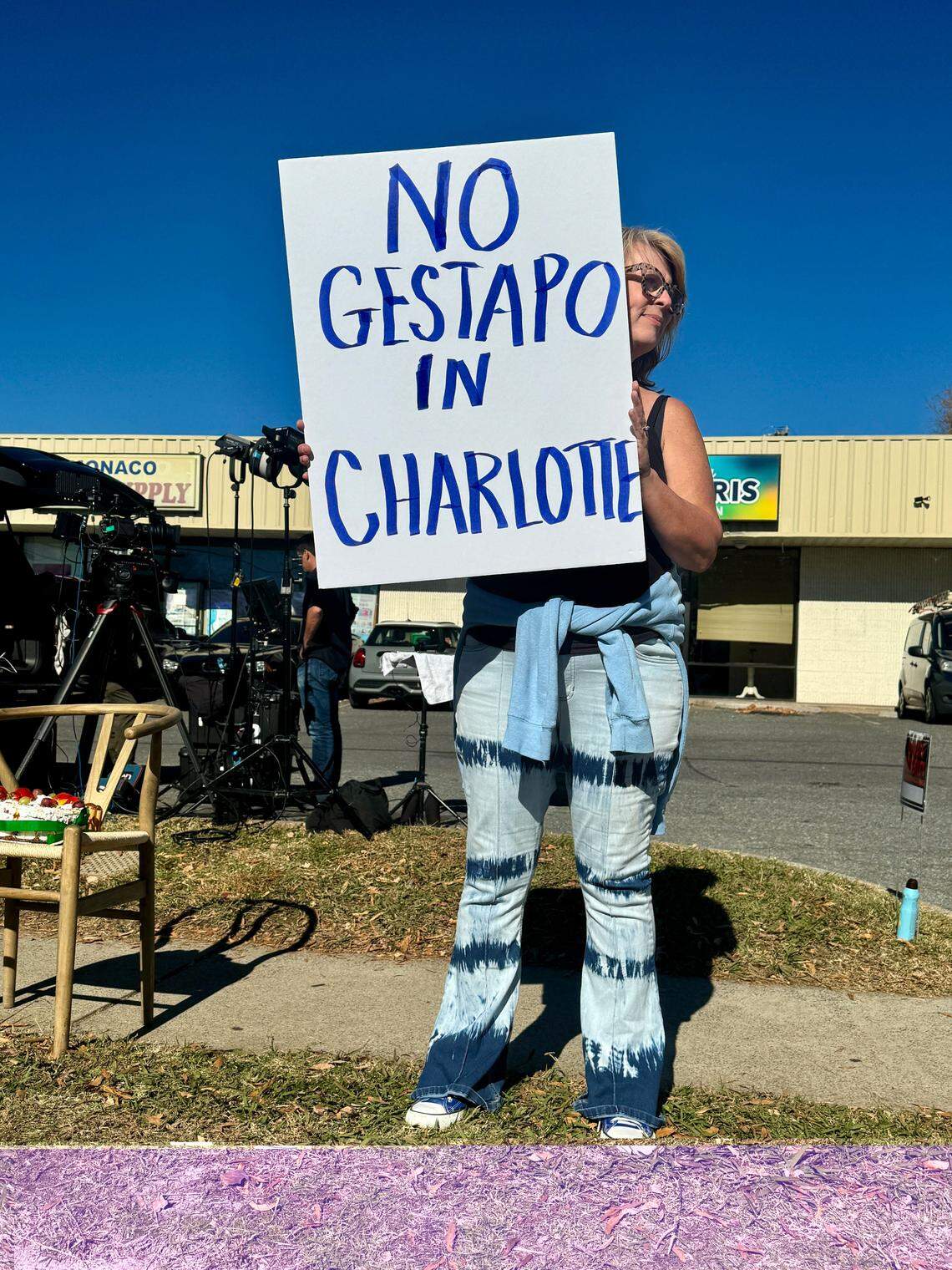 Diane Carrouth waves a sign at passing cars outside Manolo’s Bakery in east Charlotte on Monday, Nov 17, 2025. The bakery closed for the first time in 28 years after Border Patrol arrests in Charlotte. A handful of protesters gathered outside the bakery to protest ICE activity in the neighborhood.