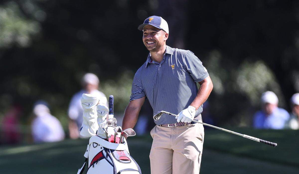 Xander Schauffele smiles as he grabs a club during the second practice round at the Presidents Cup at Quail Hollow Golf Club in Charlotte, N.C., on Wednesday, September 21, 2022.