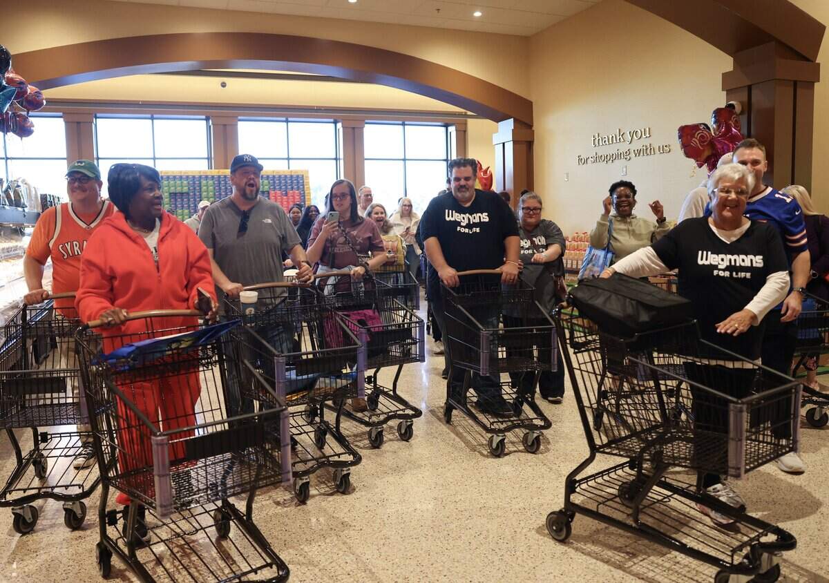 The first customers at Wegmans grocery store in Charlotte make their way past the front door Wednesday, Oct. 14, 2026 on the opening day.