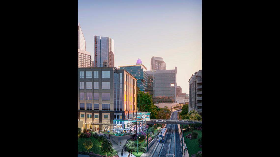 A rendering of a vibrant urban scene with a train on tracks running parallel to a multistory building with a “Market and a Table” sign. The building is surrounded by lush landscaping and people walking on a street as a modern skyline rises in the background.