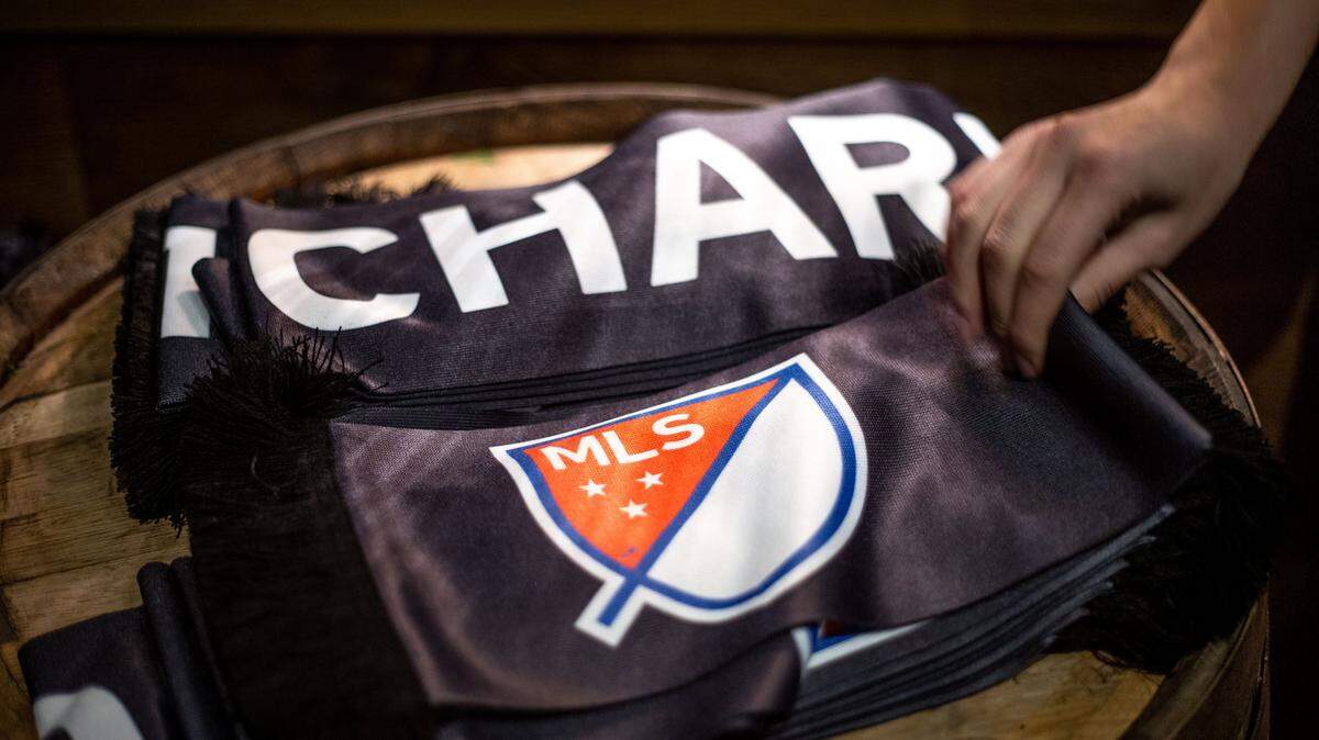 An employee hands out MLS scarves for patrons of Brewers at 4001 Yancey in Charlotte, NC on Tuesday, December 17, 2019. The celebration followed the official announcement of Charlotte becoming the 30th city to have Major League Soccer.