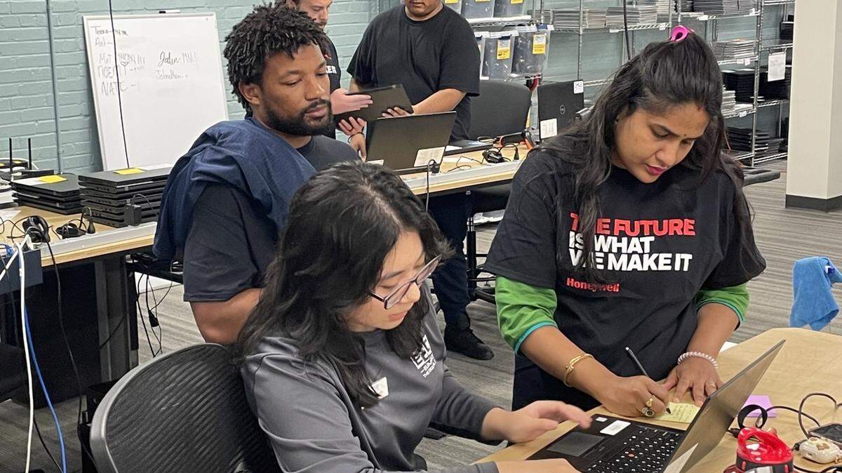 A Honeywell employee refurbishes a computer alongside students at an E2D lab. Courtesy of Honeywell