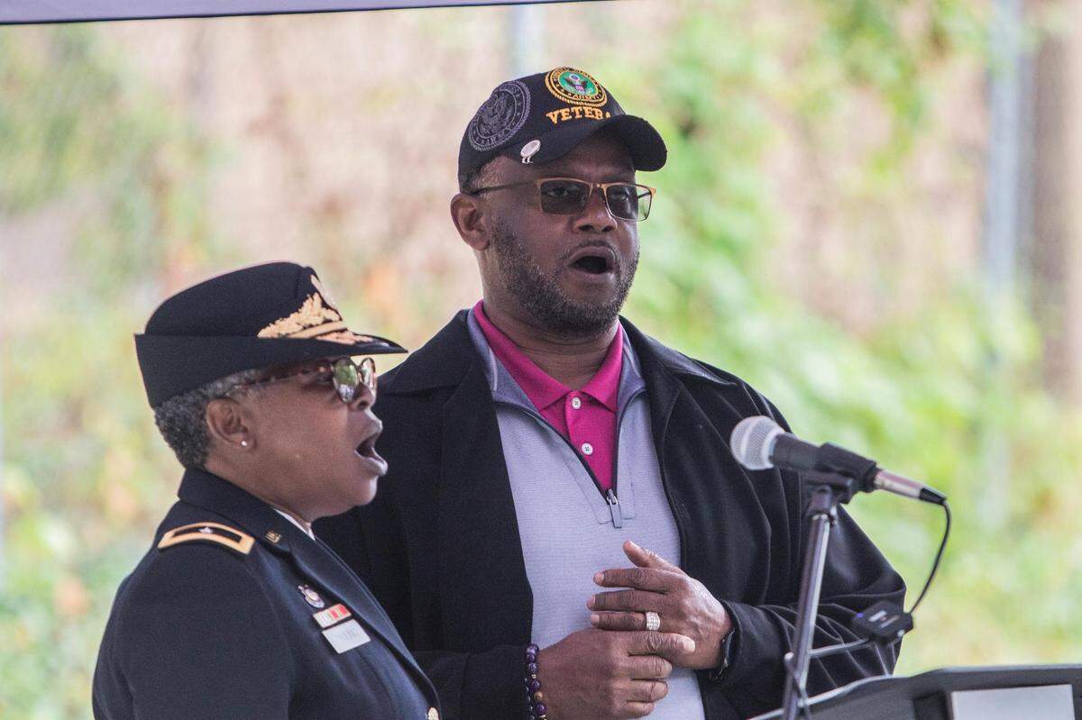 Brigadier General Tia Young and her husband First Lieutenant Tracy Young lead dozens of individuals in a song to honor veterans laid to rest at Cedar Grove Cemetery during a Memorial Day event.