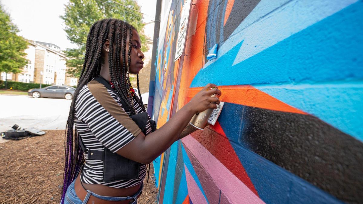 Georgie Nakima works on a new mural at South Church and Lincoln streets in Charlotte. “Stronger Together” will be part of Art Walks’ self-guided walking tour in the Gold District.