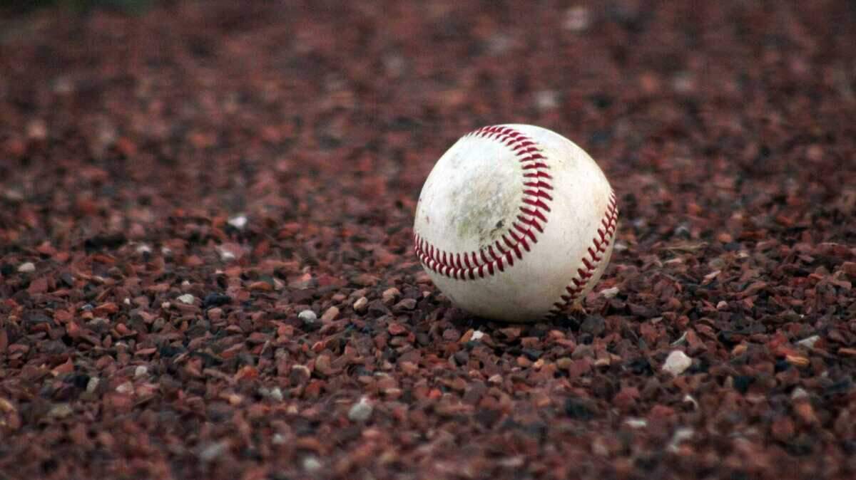 A baseball lays on the infield dirt.