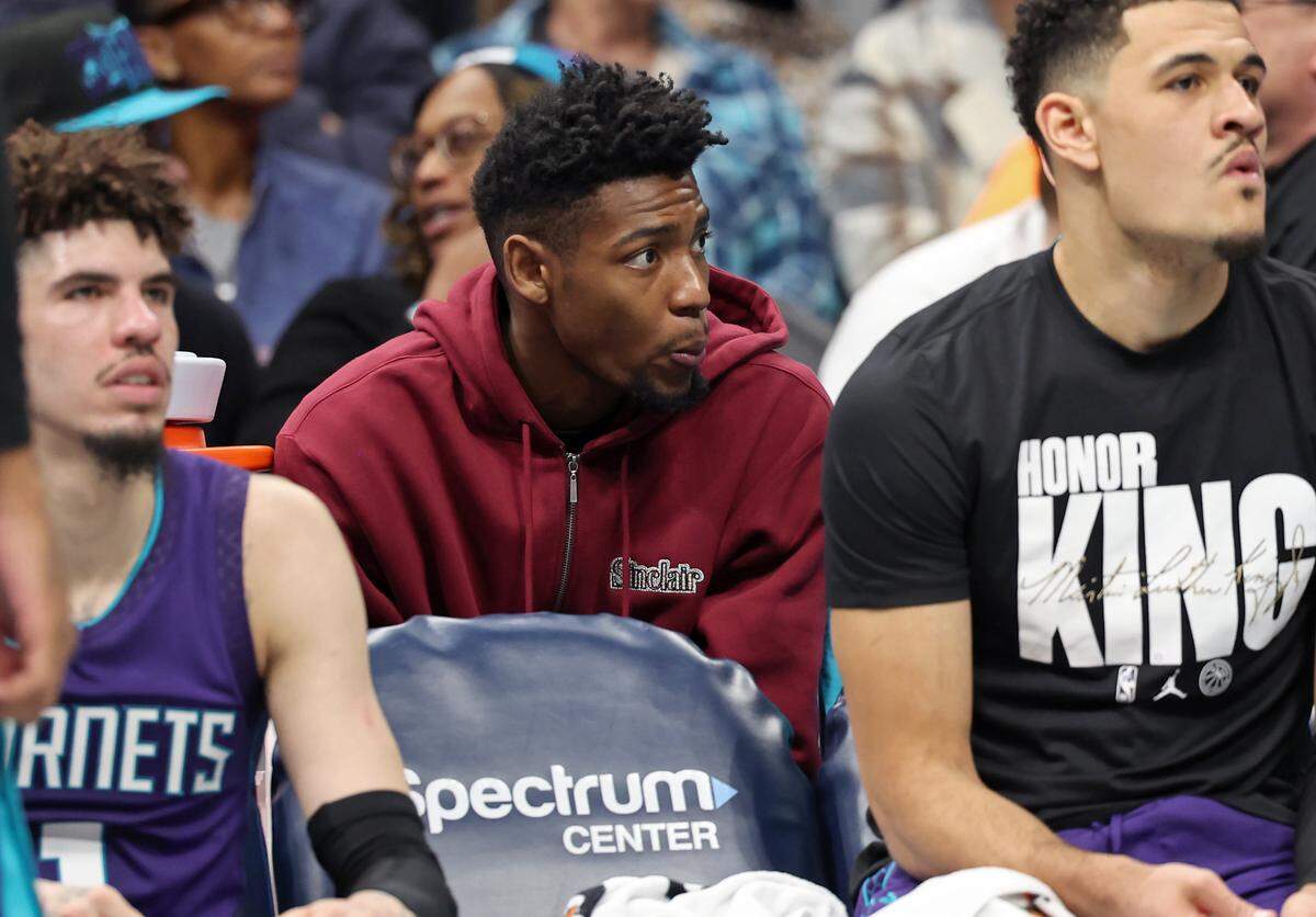 Injured Charlotte Hornets forward Brandon Miller (center) sits behind teammates LaMelo Ball (left) and Josh Green Monday. Miller is out indefinitely with a torn ligament in his right wrist.