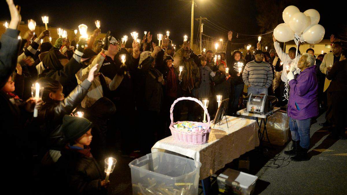 Judy Williams (right) of Mothers of Murdered Offspring leads a candlelight vigil for Keith Thomas Graham, the first homicide victim of the year, in the parking lot of the West Charlotte Recreation Center on January 26, 2014.