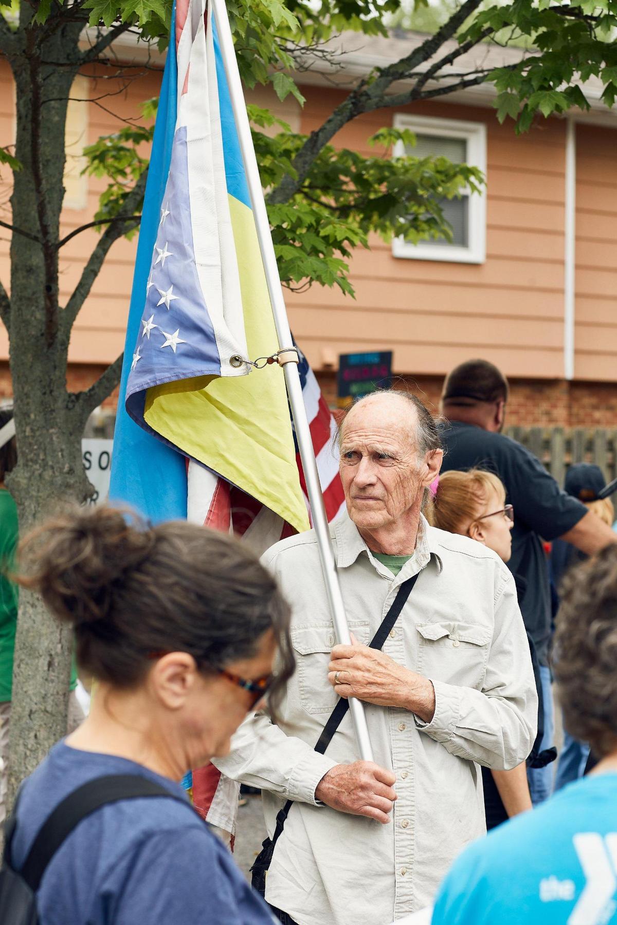 A man stands with U.S. and Ukrainian flags at an anti-Trump protest in Charlotte on Saturday.