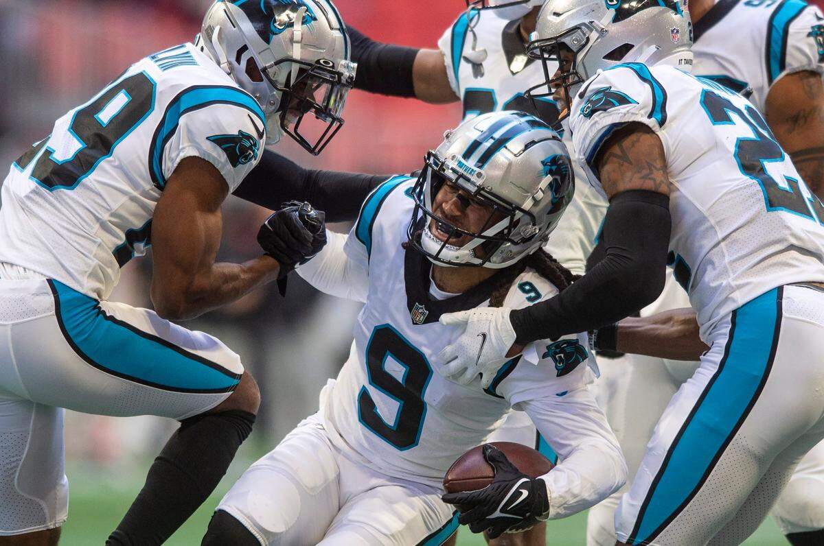 Panthers cornerback Stephon Gilmore, center, is helped up by teammates after making an interception during the game against the Falcons at Mercedes-Benz Stadium on Sunday, October 31, 2021 in Atlanta, GA.