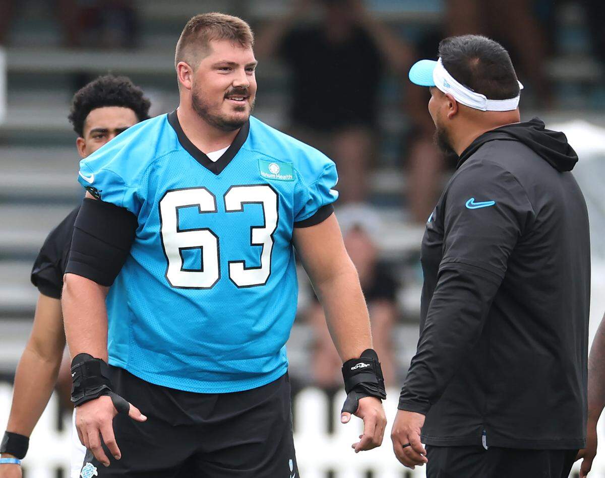 Carolina Panthers center Austin Corbett, center, speaks to assistant OL coach Keli’i Kekuewa after snapping the ball to quarterback Bryce Young during training camp practice on Thursday, July 25, 2024.