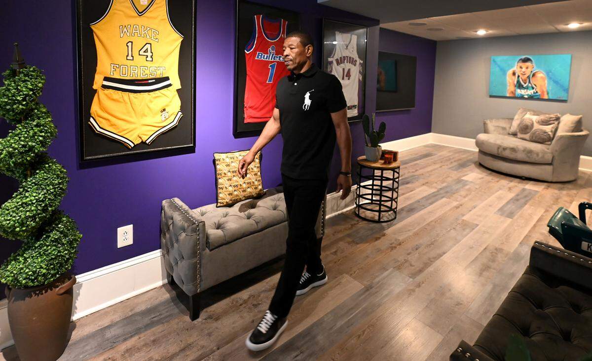 Former Charlotte Hornets guard Muggsy Bogues walks beside some of his memorabilia at his Charlotte home.