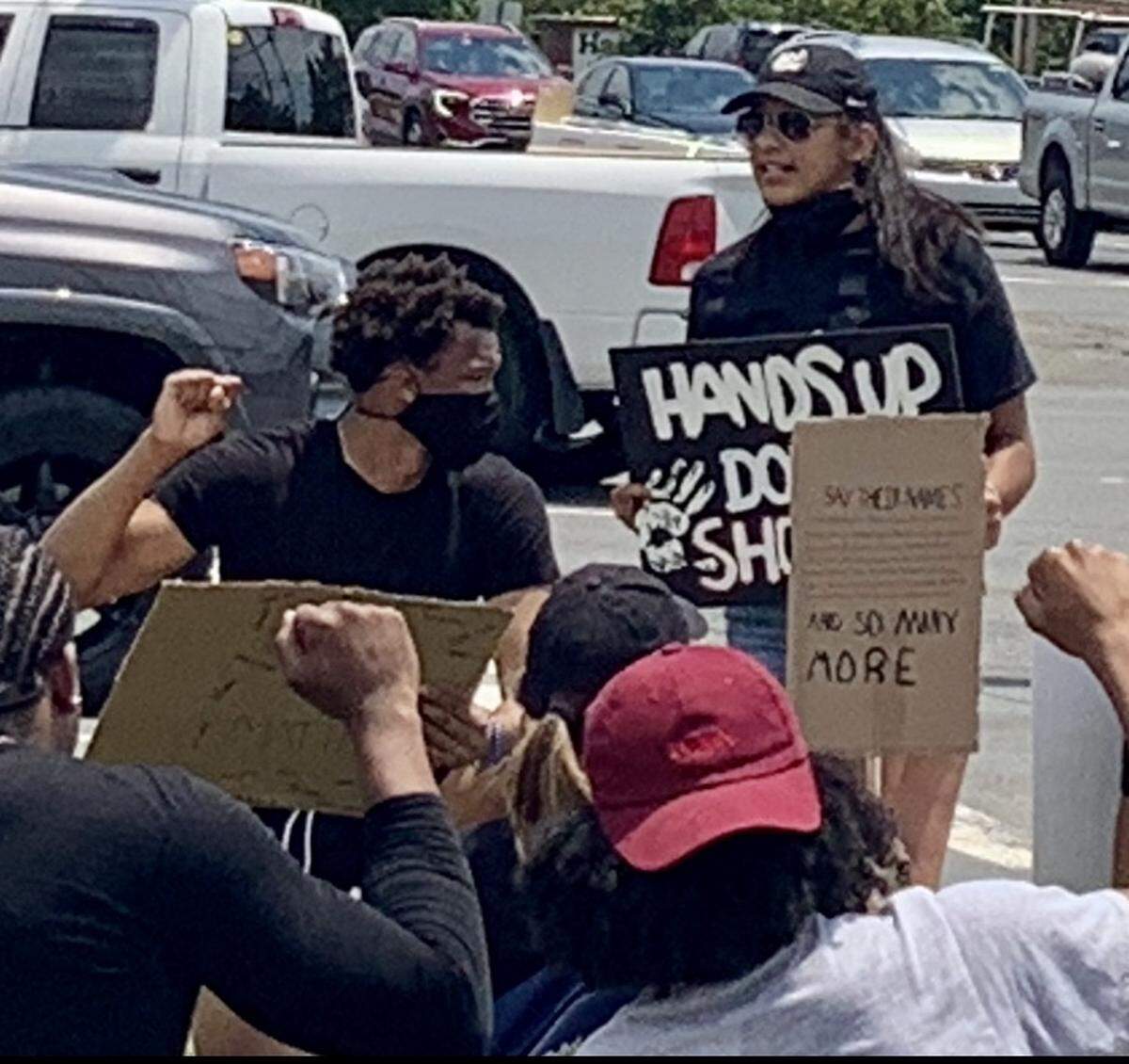 Wendell Moore, the current Duke and former Concord Cox Mill basketball star, kneels while raising a fist at the “Black Lives Matter” protest he helped organize and lead Saturday. Moore and his girlfriend Marissa Moyer (right, speaking) organized the protest.