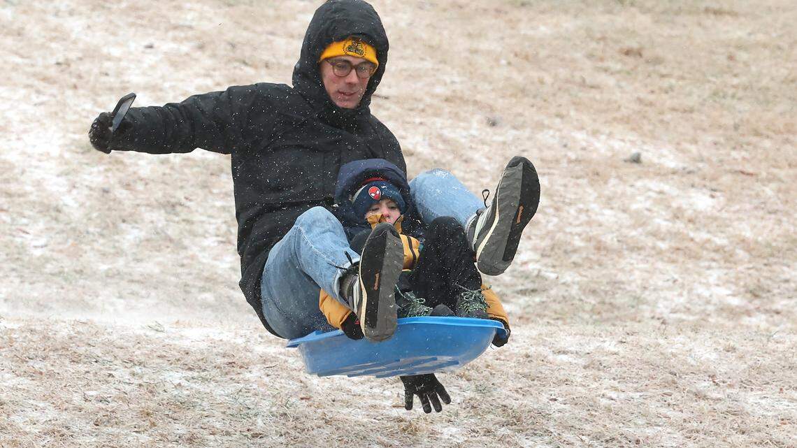 Will Young and his son, Oliver Young, five-year old, catch air as they slide down a hill at Veterans Park in Charlotte, NC on Sunday, January 25, 2026. The Charlotte area received a wintry mix of ice, freezing rain and light snow.