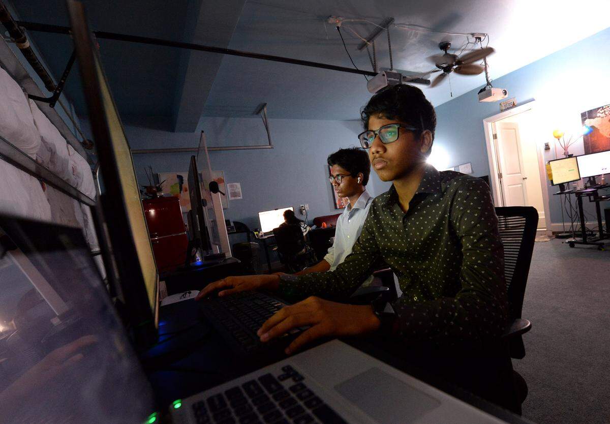 Kamal Yerra, pictured in the foreground, and his older brother Shashi work at their desks in the garage of their family’s Fort Mill, S.C. home. Says Shashi: “People are having $100,000, $200,000 in debt just from student loans, and if people can do this — if I could do this with just a fraction of what that cost them, we have the same amount of credits and I spent less — that could be a great help for households, for people who ... can’t afford the normal amount.”