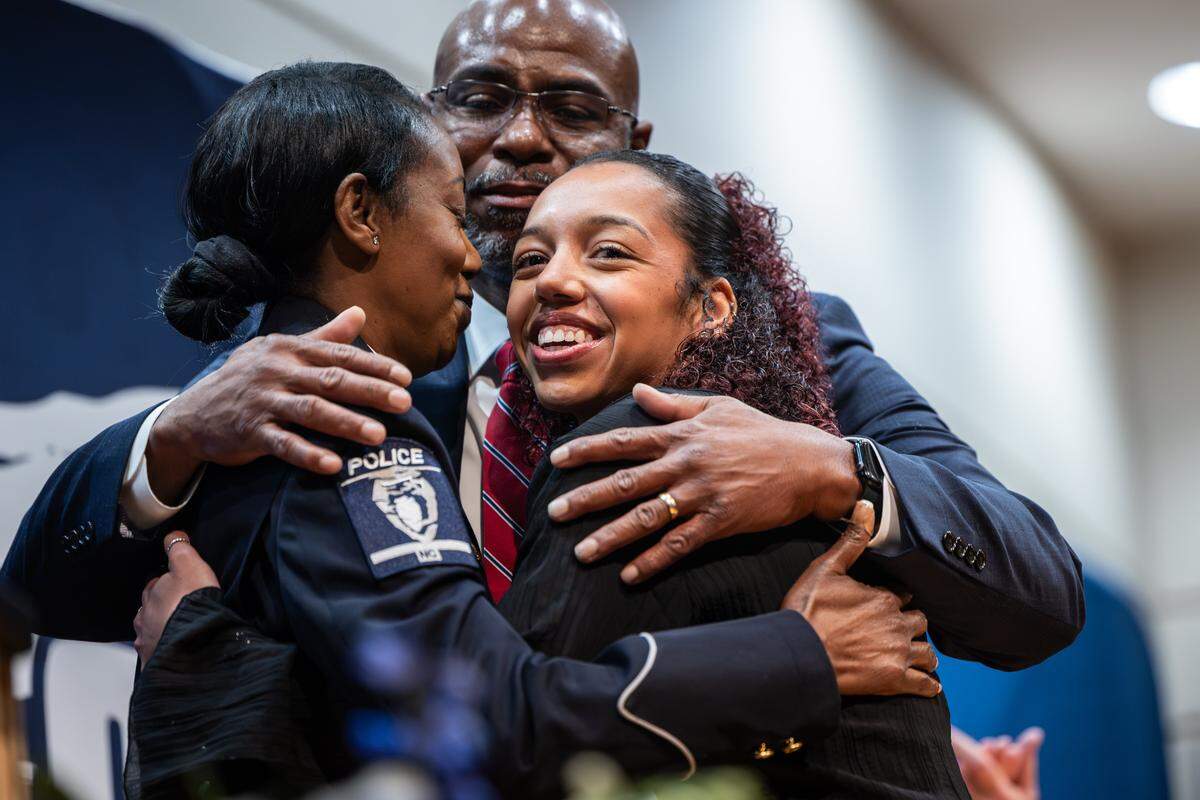 Chief Estella Patterson, left, shares a hug with her husband, Lance and her niece, Jaelynn Holder, during her swearing in ceremony at the Charlotte Police and Fire Training Academy in Charlotte on December 5, 2025.
