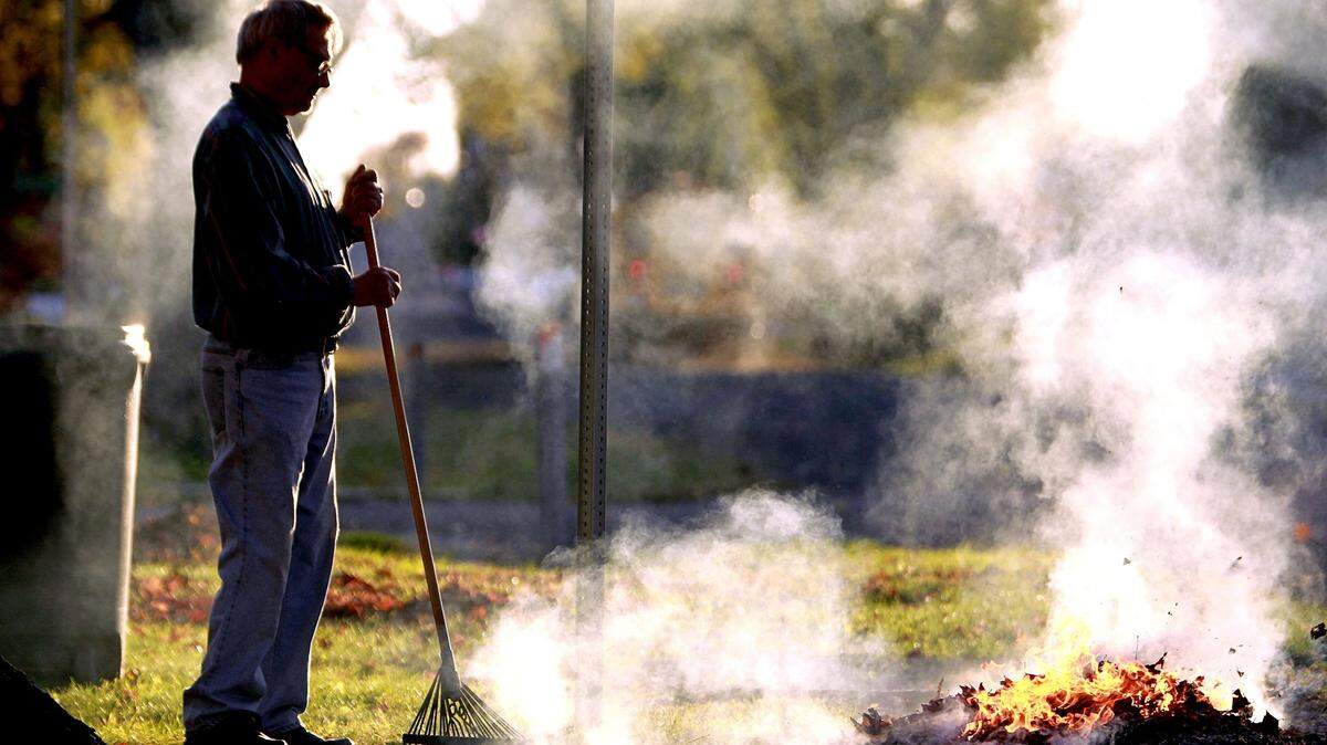 Vernon Werle of Caseyville, Illinois, stands by while burning the leaves in the front yard of his home.