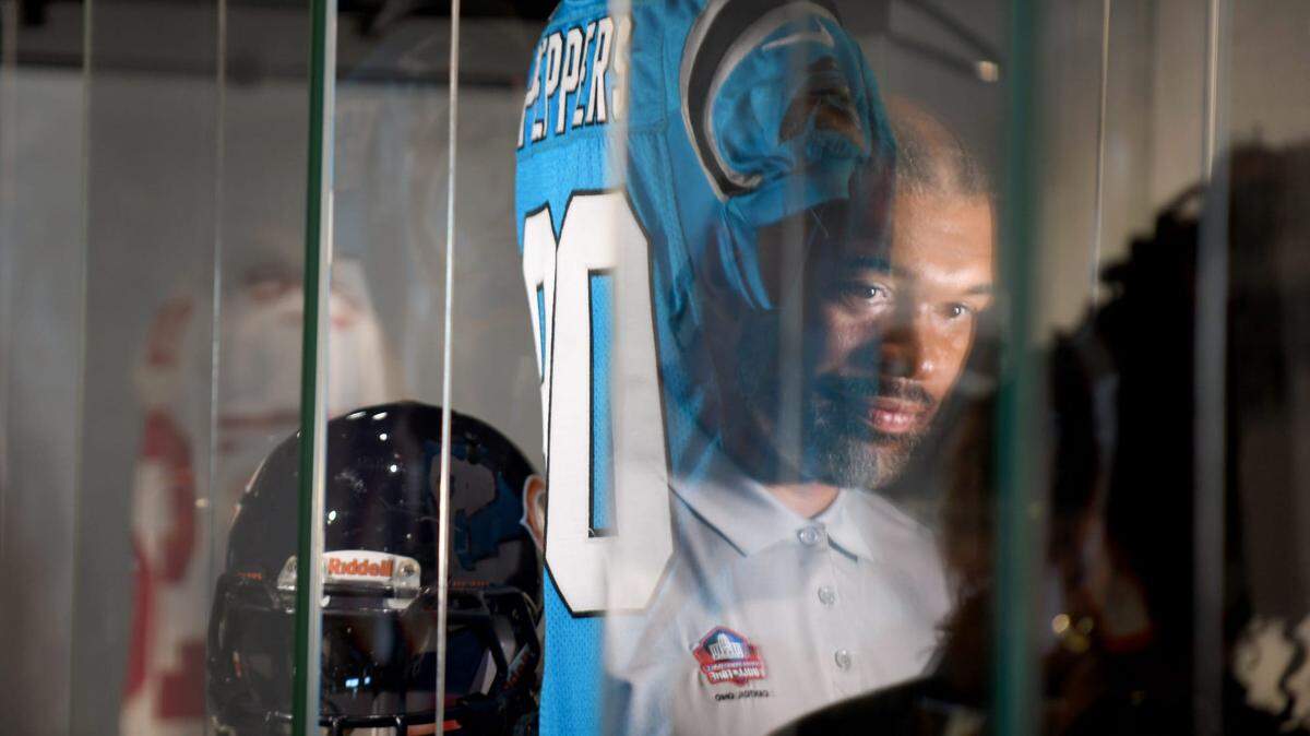 Julius Pepper, a member of the Pro Football Hall of Fame’s Class of 2024, is reflected in a glass case of his memorabilia as he is interviewed during a visit to the Hall, Friday, May 24, 2024.