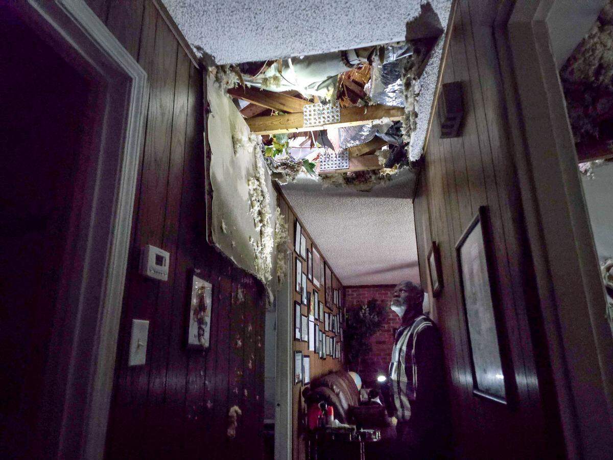 McKinley Moore inspects the damage on his home after a tree fell over his bedroom early Friday morning Sept. 27, 2024 in Charlotte. The ceiling fan and ceiling fell on top of him. He lives at 5635 Lawn Meadow Drive