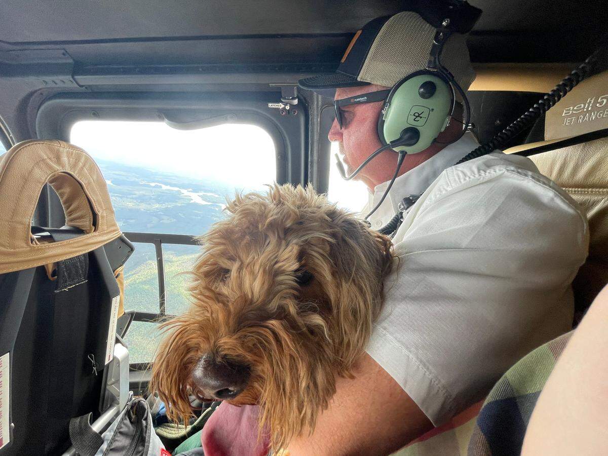 A fire marshal holds 71-year-old Katherine’s dog, Sassy, after the private helicopter he’s hitching a ride on rescued the pair from Barnardsville, 20 miles north of Asheville.