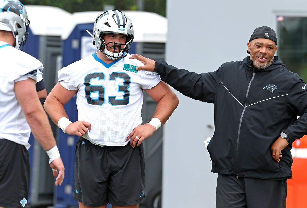Carolina Panthers center Austin Corbett, center and Assistant Head Coach/ Run Game Coordinator Harold Goodwin, right, watch players run through a drill with during the team’s OTA practice on Tuesday, May 27, 2025.