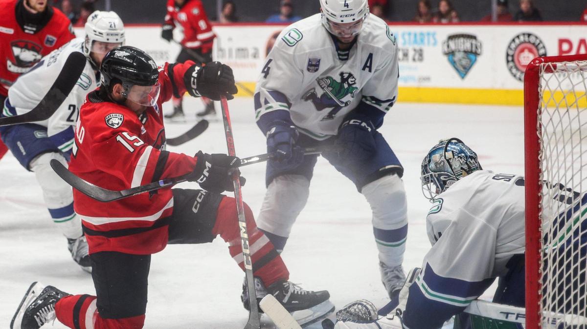 Checkers center Kyle Criscuolo, left, struggles to get the puck into the net as Canucks defender Jett Woo, center, and goalie Arturs Šilovs block during the Calder Cup opener at Bojangles Coliseum in Charlotte, NC on Friday, June 13, 2025.