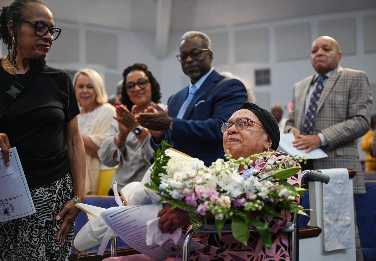 Ms. Lallage M. Caouthers, RN, BSN, center, receives flowers and a stading ovation during an unveiling ceremony at Ebenezer Baptist Church for an NC highway historical marker recognizing Good Samaritan Hospital in Charlotte on Thursday, May 28, 2026. Carouthers, who is 89 years old, was part of the Good Samartian nursing graduating class of 1957. Good Samartian Hospital was built to serve the medical needs of Black people in Charlotte. Additionally, it was the first privately funded hospital in North Carolina which served Black patients. The original building was destroyed in 1996 to make way for construction of what is now Bank of America Stadium.