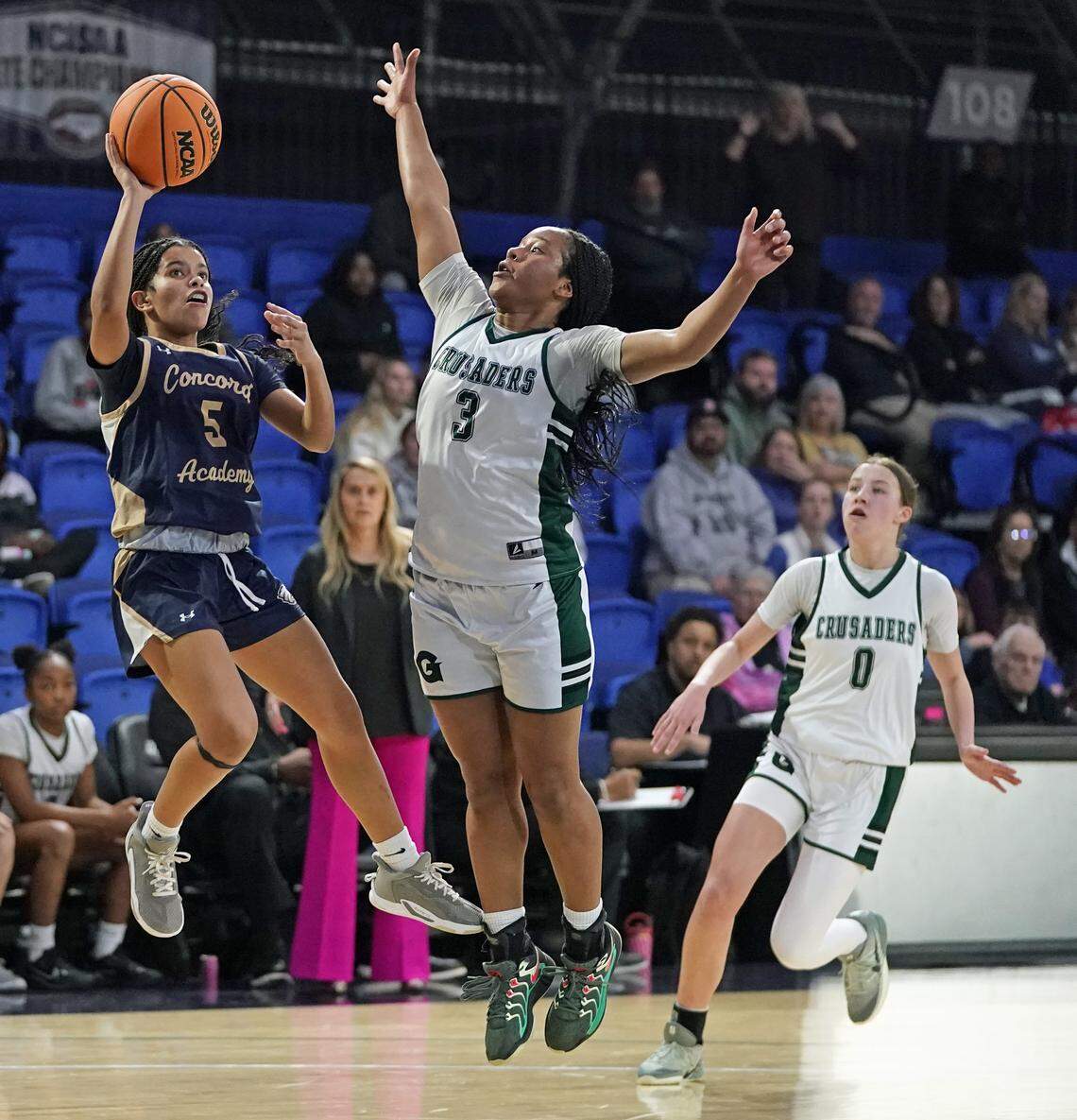 Concord Academy's Quinn Hicks, left, gets off a shot over Grace Christian's Korryn Davis, center, as teammate Lola Vanore looks on during the first half of their N.C. Independent Schools Athletic Association 3A girls state championship game Friday, Feb. 27, 2026, in Greensboro, N.C. (Credit: Bill Kiser/Special to the Charlotte Observer)