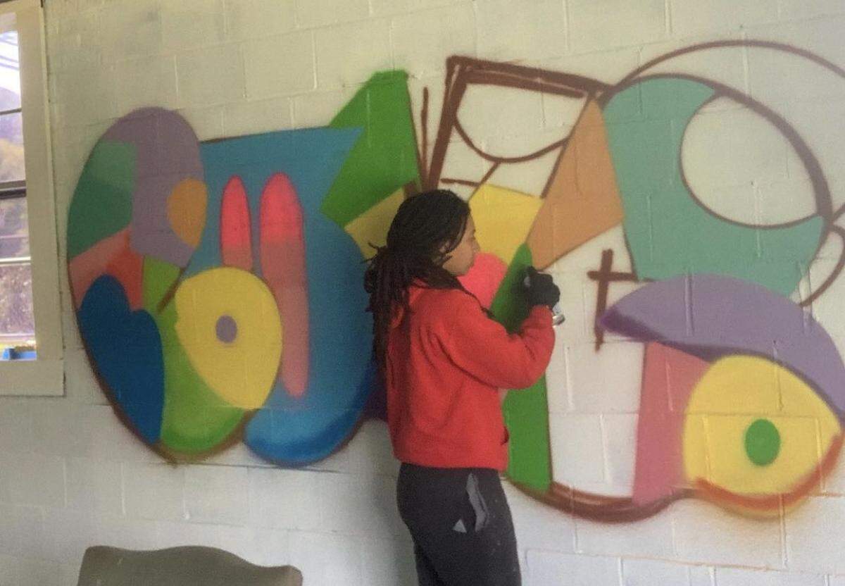 Local artist DeNeer Davis paints a mural in the new space.