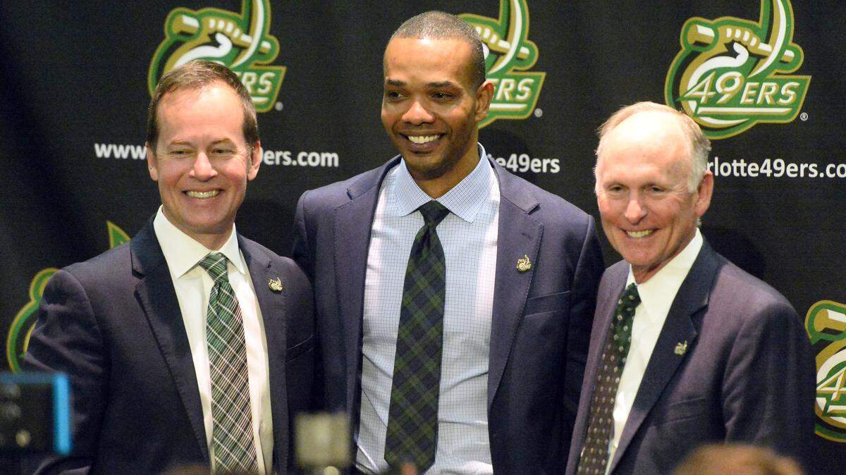 Charlotte 49ers Director of Athletics Mike Hill, left, and Chancellor Philip Dubois, right, take photos with new Charlotte 49ers men's   basketball coach Ron Sanchez at his introductory news conference on March 27.