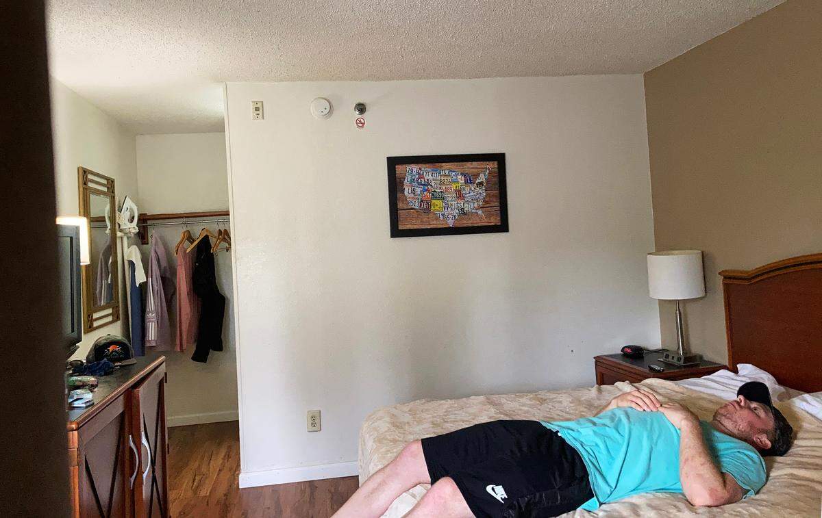 Aaron Hall set his phone up to take a photo of himself on the bed of a hotel room he stayed in in Charlotte while he was sick with COVID-19.