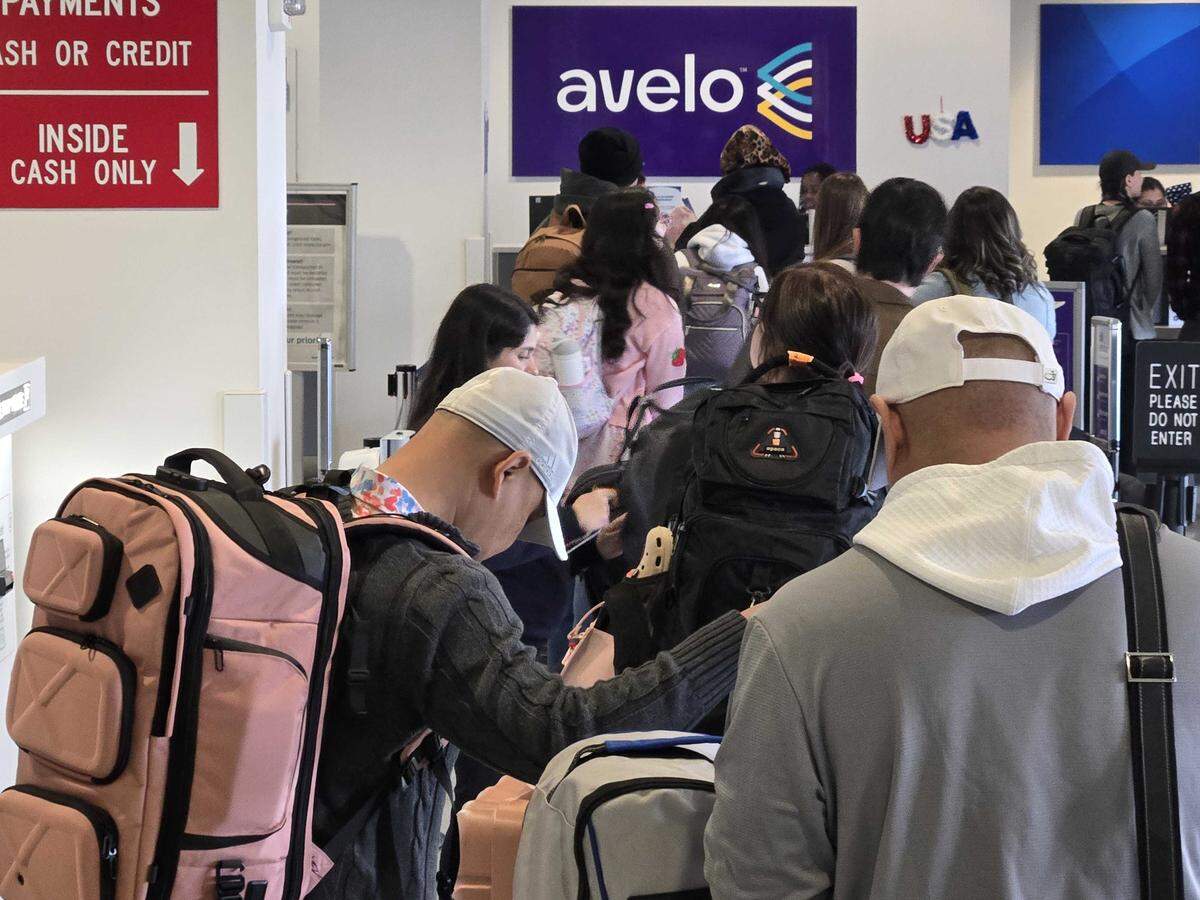Avelo Airlines Passengers at Concord-Padgett Regional Airport wait in line to board a flight.