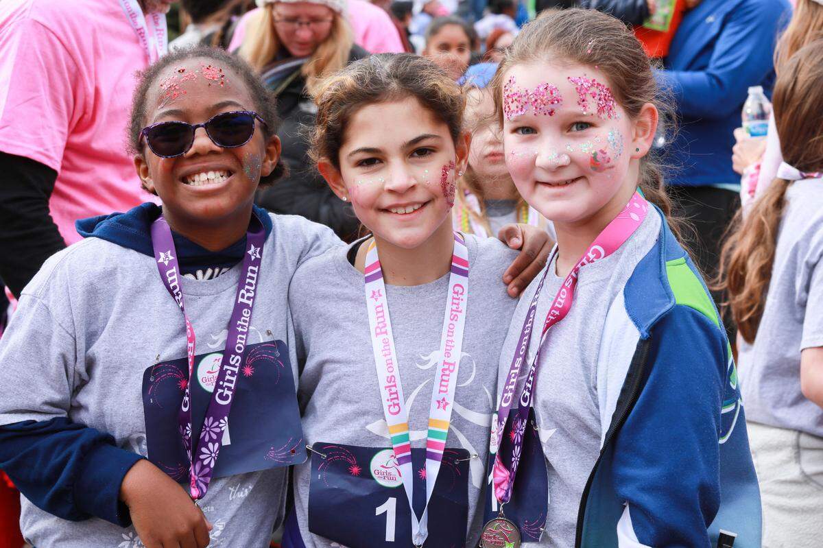 Three young participants in a “Girls on the Run” 5-kilometer run in Charlotte in December 2022 pose for a photo.