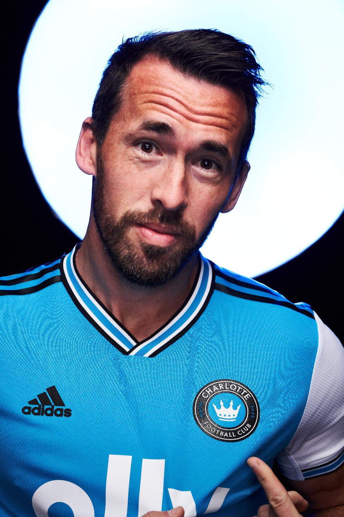 Charlotte FC soccer player Christian Fuchs points to the team’s logo. Fuchs, a defender from Austria with vast international experience, was one of the first players the team signed.
