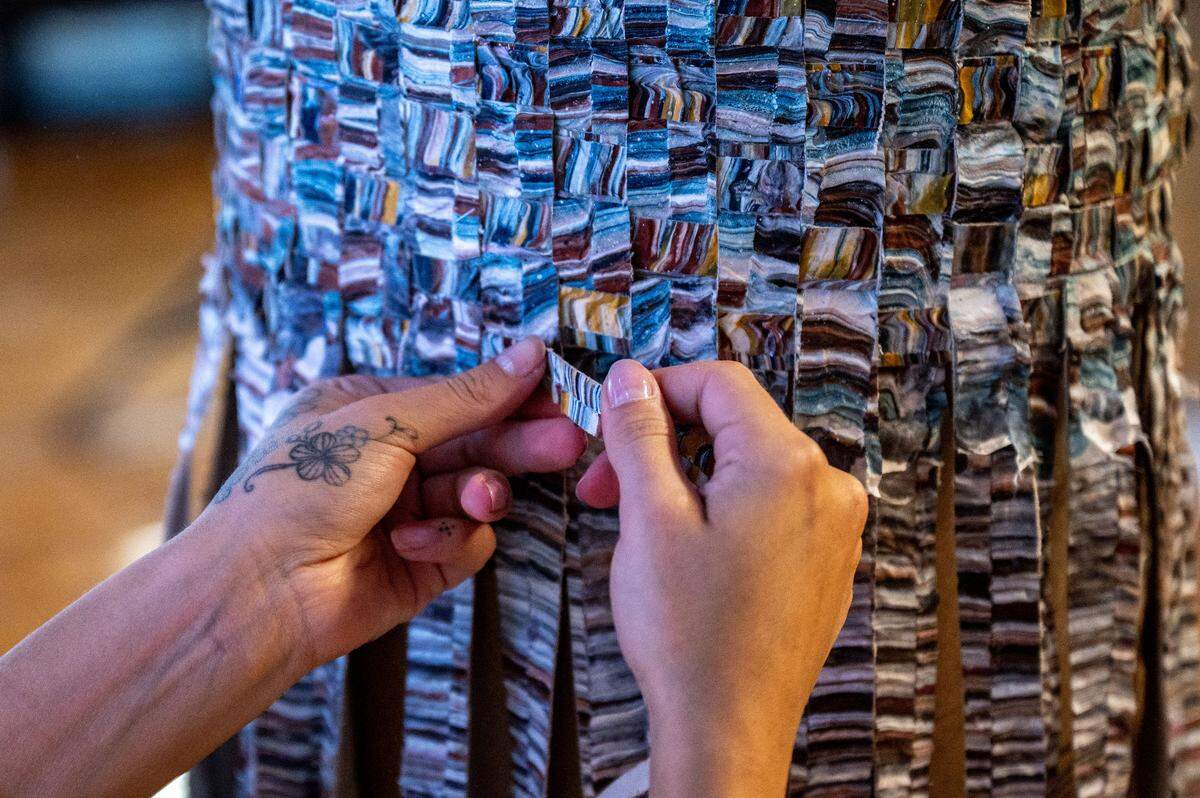 Vera Falkner, one of Kenny Nguyen’s assistants and a student at UNC Charlotte, weaves strips of silk dipped in paint around a plaster column in Nguyen’s Concord studio in Concord, NC, Tuesday August 1, 2025.