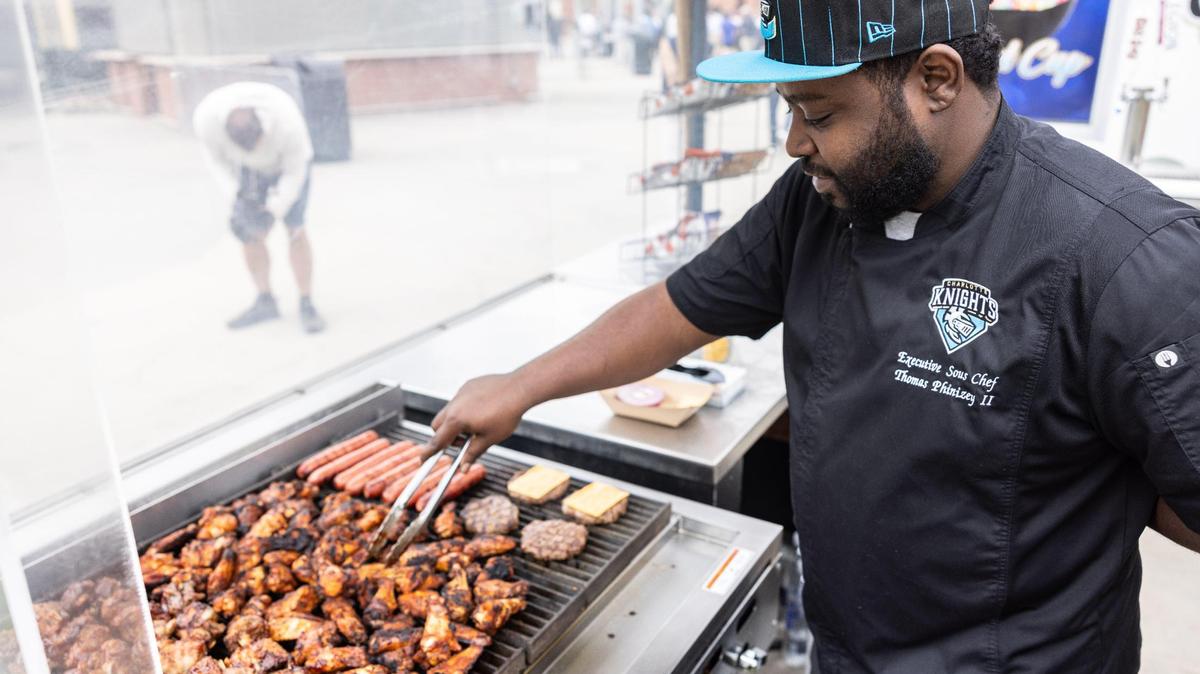 Executive Sous Chef Thomas Phinizey cooks meat on a grill during a preseason media day at Truist Field in Charlotte, N.C., on Thursday, March 28, 2024.
